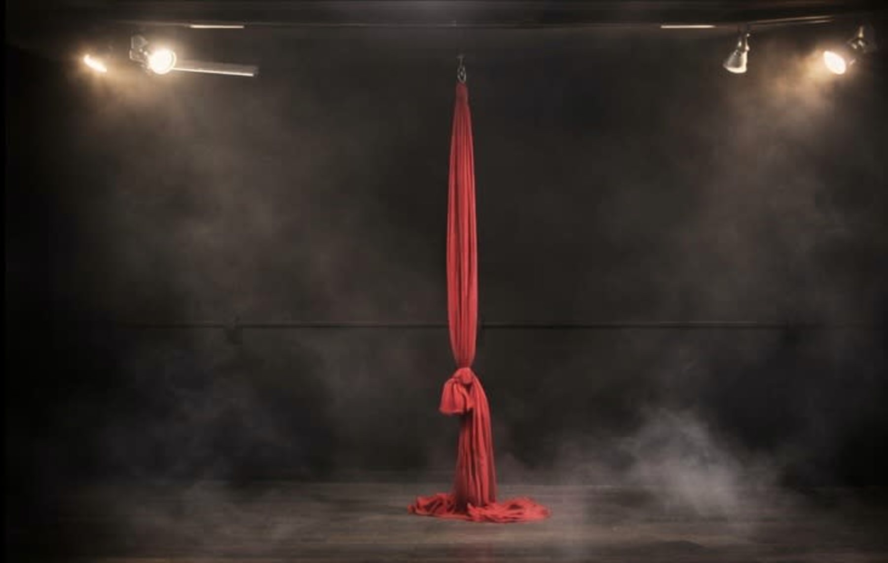 Aerial silk hanging in the hazy, warm-lit black box